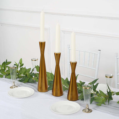 Gold candle holders with white candles on a decorated dining table.