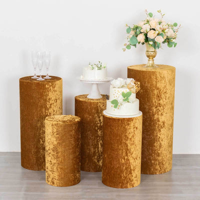 Gold velvet display pedestals for events with floral arrangements and cakes.