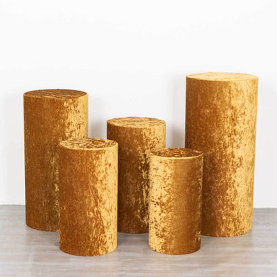 Gold velvet pedestals in various heights on a plain background.