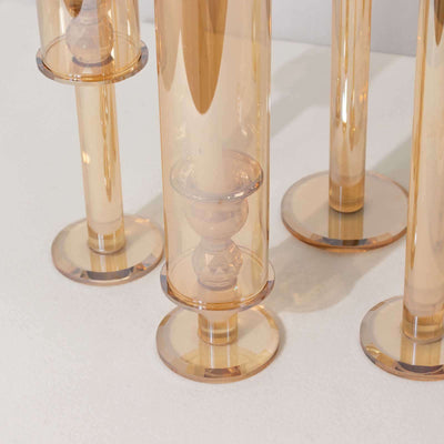 Amber glass candle holders in varying heights on a white surface.