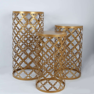 Set of three gold decorative side tables with intricate geometric designs.