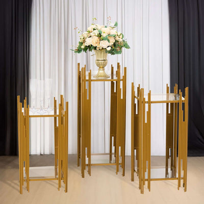 Elegant gold display stands with glass tops and a floral arrangement.