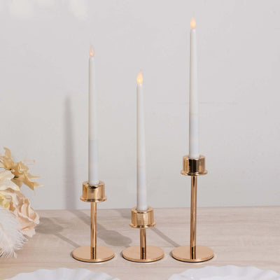 Set of three elegant gold candle holders with white candles.