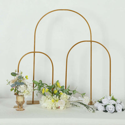 Decorative arch stands with flowers on a table.