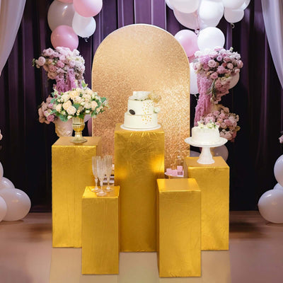 Elegant gold pedestal display with cakes and flowers for a festive celebration.