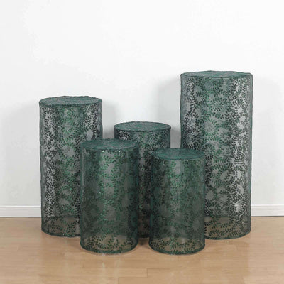 Set of five decorative green cylindrical planters with intricate patterns.