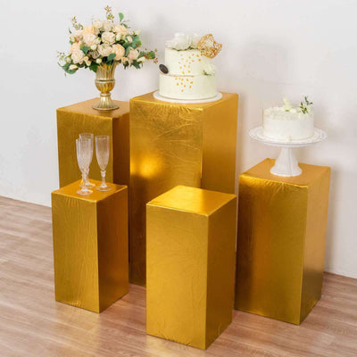Gold display pedestals with cakes and floral arrangements for event styling.