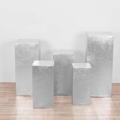 Silver display pedestals in various heights on a wooden floor.