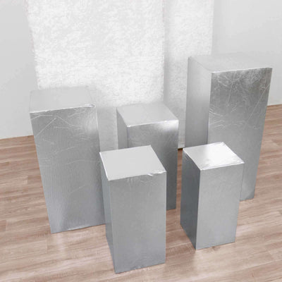 Silver display pedestals in various heights on a neutral backdrop.