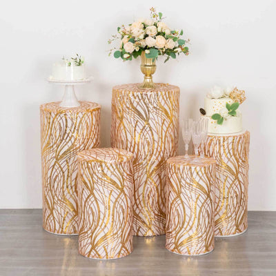 Decorative cake stands with gold pattern and floral arrangement on a neutral backdrop.