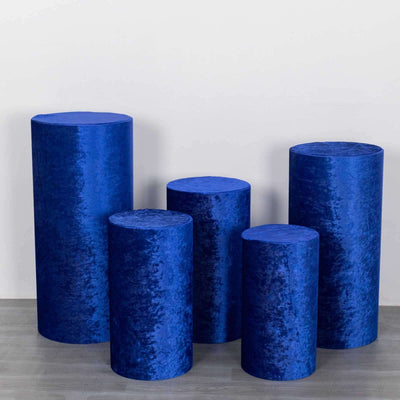 Blue velvet display pedestals in varying heights arranged on a gray floor.