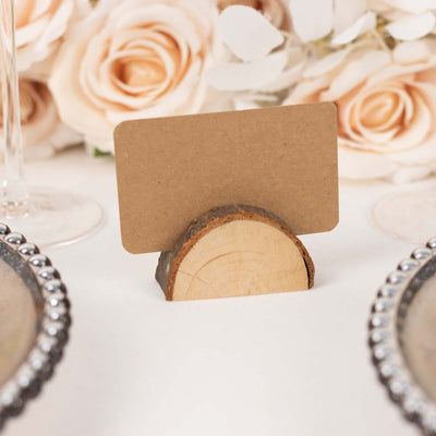 Wooden place card holder with blank card, surrounded by roses.