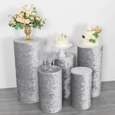 Decorative gray pedestals with floral arrangement and cakes displayed on top.