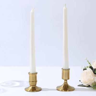 Brass candle holders with white candles on a plain background