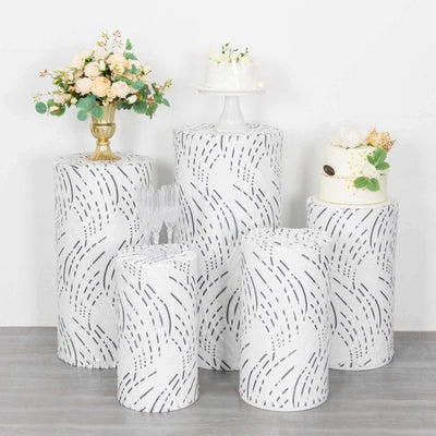 Decorative cake and display pedestals with floral arrangements on a white backdrop.