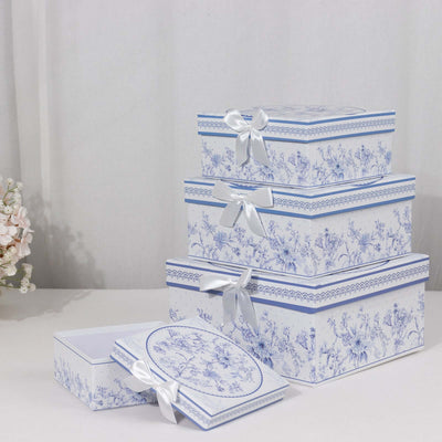 Stacked decorative gift boxes with floral design and ribbons on a plain backdrop.