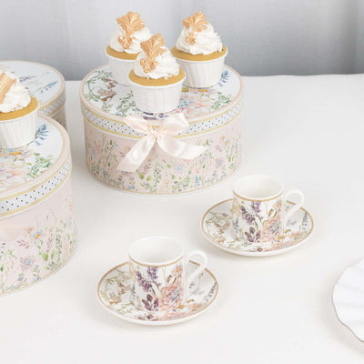 Elegant porcelain tea set with floral design and cupcakes in decorative boxes.