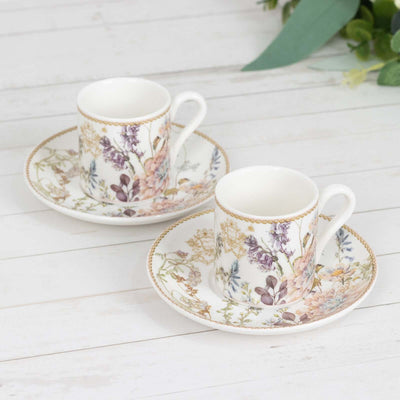 Floral porcelain cups and saucers set on a wooden table.