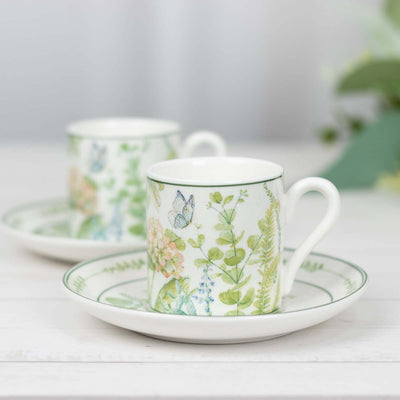 Floral pattern teacup and saucer set on a white wooden surface.