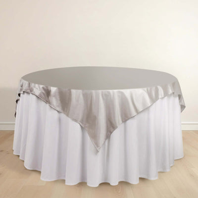 Round table with a silver satin tablecloth and white skirt