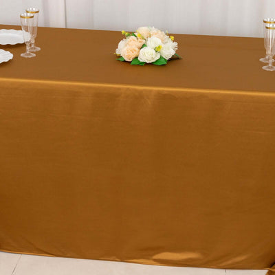 Gold tablecloth draped elegantly on a table with floral centerpiece.