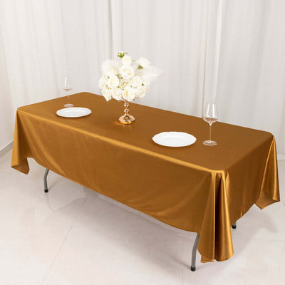 Elegant gold tablecloth with white plates and floral centerpiece on a table.