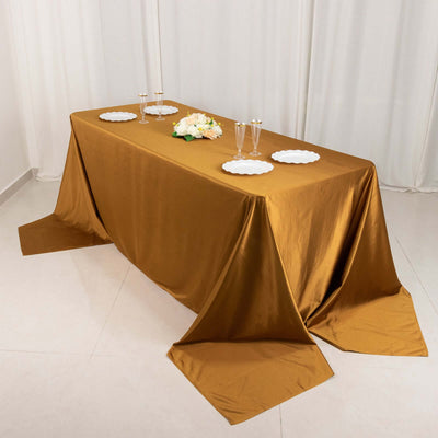 Elegant gold tablecloth draped over a table with plates and glasses.