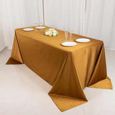 Gold tablecloth draped elegantly on a table with floral centerpiece and dinnerware.