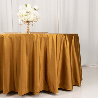 Gold satin tablecloth draped over a round table with floral centerpiece.