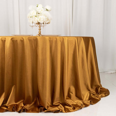 Gold satin tablecloth draping elegantly on a table with white roses centerpiece.