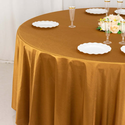 Brown tablecloth draped over a round table with white plates and floral centerpiece.