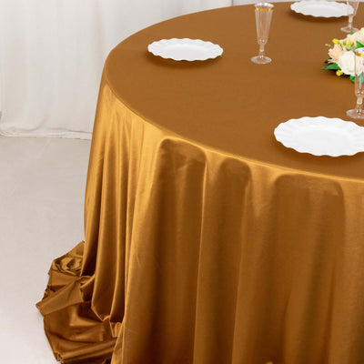 Elegant brown tablecloth draping over a round table with white plates and floral centerpiece.