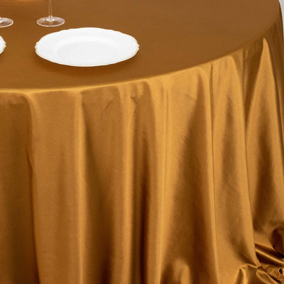 Elegant gold tablecloth with white plates for dining setup.
