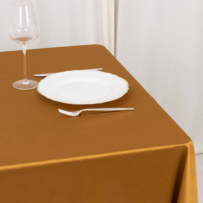 Elegant table setting with a white plate, glass, and silverware on a brown tablecloth.