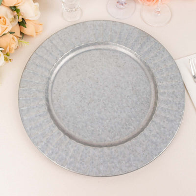 Galvanized metal charger plate on a table with floral decor.