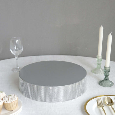 Round gray cake stand with silver accents on a table setting.