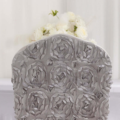Silver rose-patterned chair back with white floral arrangement in the background.