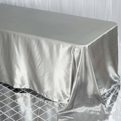 Silver satin tablecloth draping over a table with a reflective base.