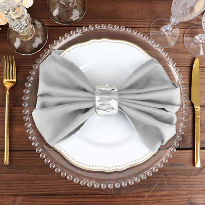 Elegant gray napkin tied with a crystal ring on a decorative dinner plate.