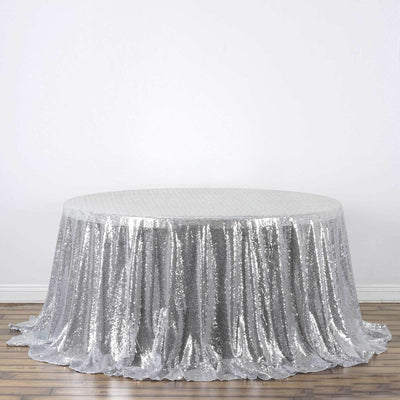 Silver sequin tablecloth in a round shape on a plain backdrop.