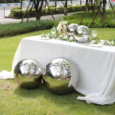 Reflective metallic spheres on a table with floral decor in an outdoor setting.
