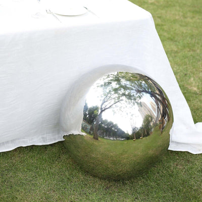 Shiny reflective sphere on grass beside a table with a white tablecloth.