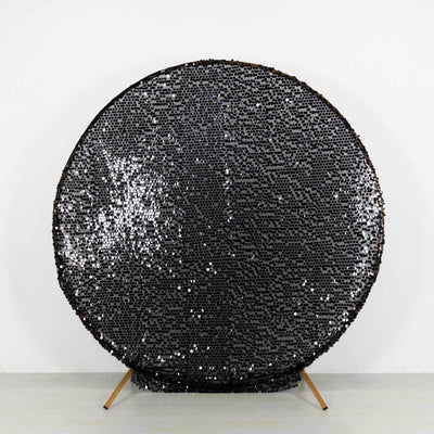 Black circular mirror sculpture with a textured surface.