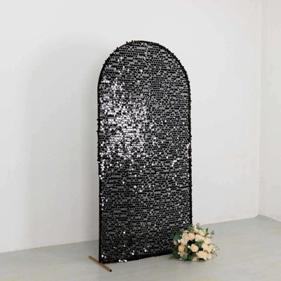 Black decorative mirror with an arched top and a shimmering surface.