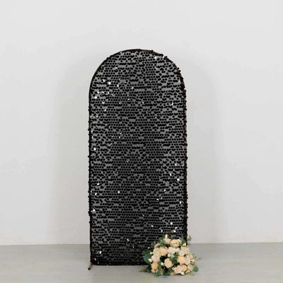 Black sequin arch backdrop with floral arrangement at the base.