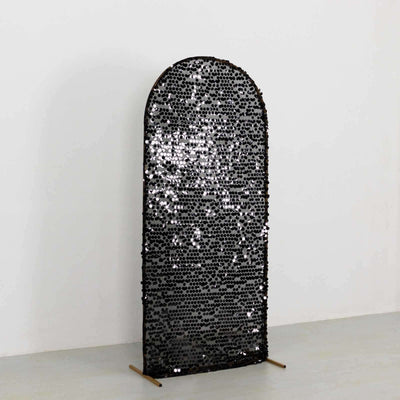Black sequin room divider with an arched top on a plain backdrop.