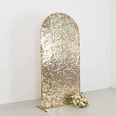 Gold sequined arch backdrop with floral arrangement.