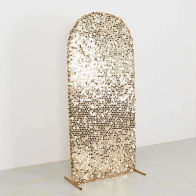 Gold sequined arch mirror on a stand against a plain background.