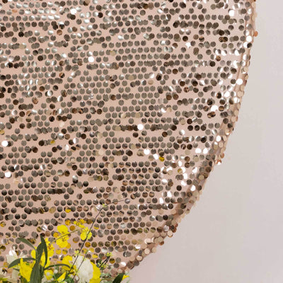 Shiny rose gold sequin backdrop with floral arrangement at the bottom.
