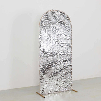 Decorative arched mirror with a silver mosaic design on a stand.